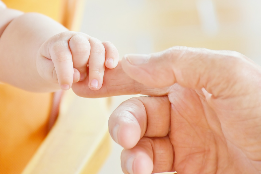 mains de bébé et doigt d'ostéopathe