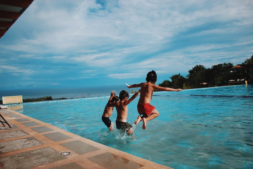 3 enfants sautant dans une piscine